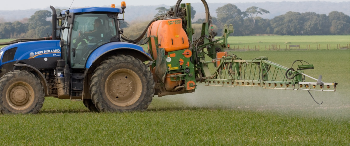 A tractor sprays pesticides onto a field.