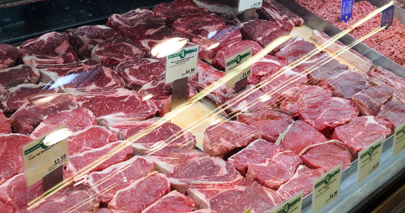 Cuts of meat lay arranged behind the glass at a deli counter.