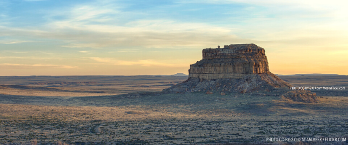 A mesa rises over a flat landscape and blue skies in Chaco Canyon National Park--one of the parks that could be saved if Biden bans new oil and gas operations on federal lands.