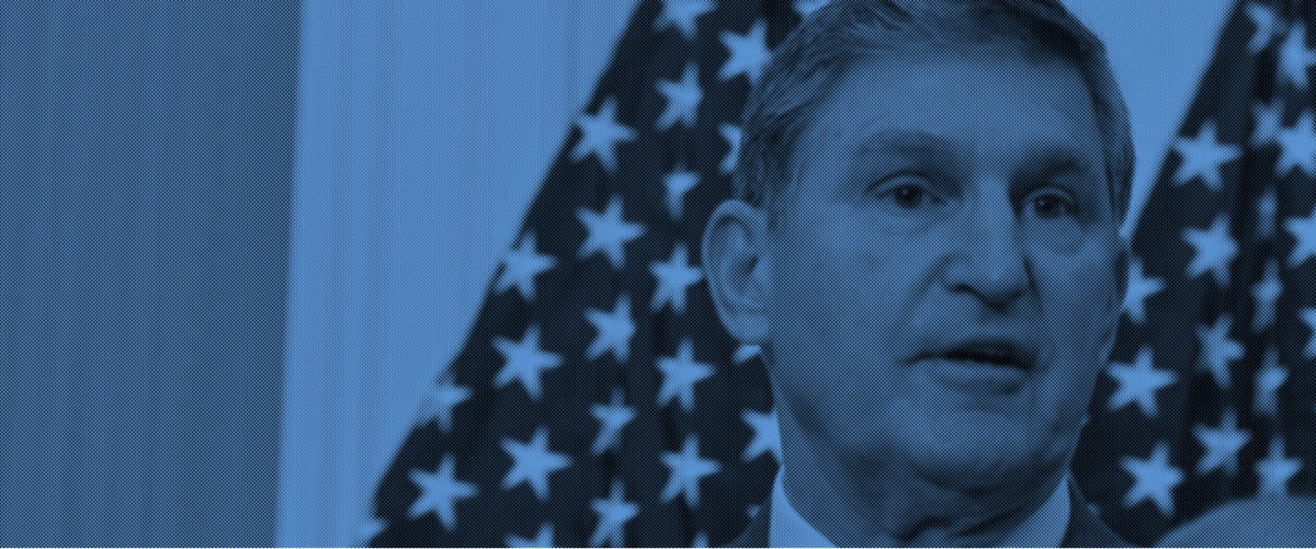 Sen. Joe Manchin stands in front of American flags.