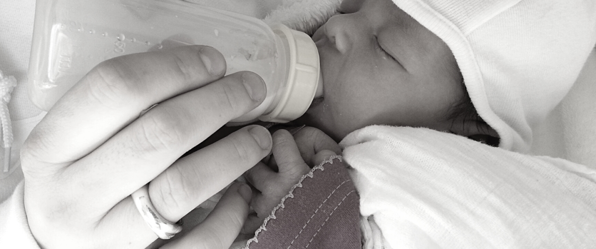 A hand feeds a baby from a bottle. Formula-fed babies are at greater risk of experiencing the health impacts of fluoridated water.