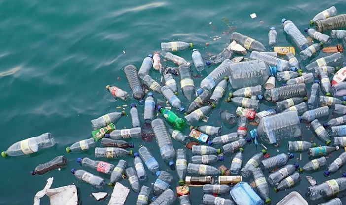 Empty plastic bottles made from fracking float in blue water.