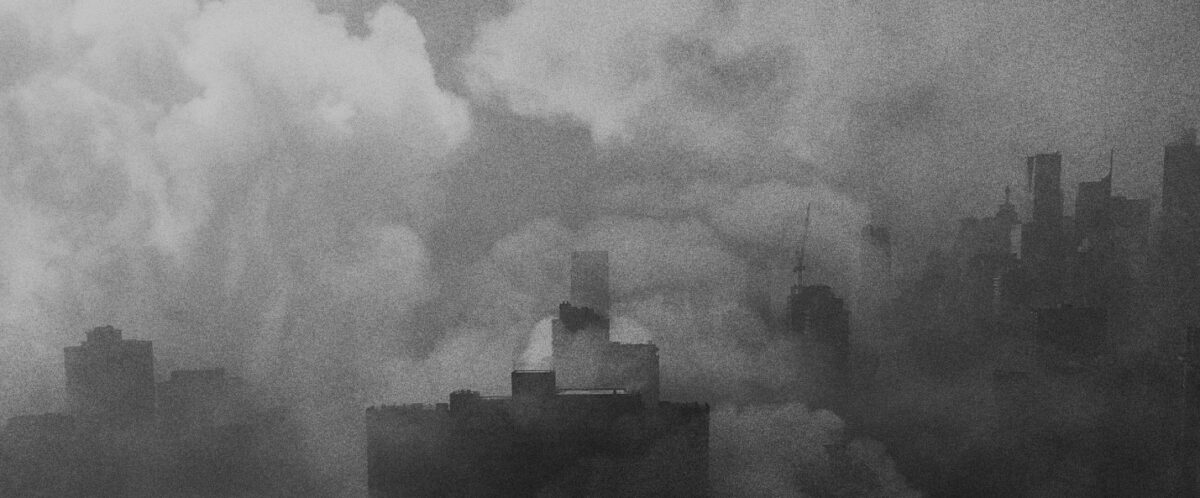 Clouds of haze and smoke hover over a gray skyline.