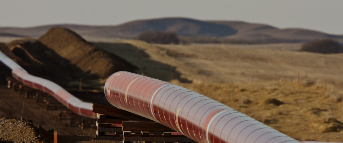 A red gas pipeline runs through mountains and a brown landscape.