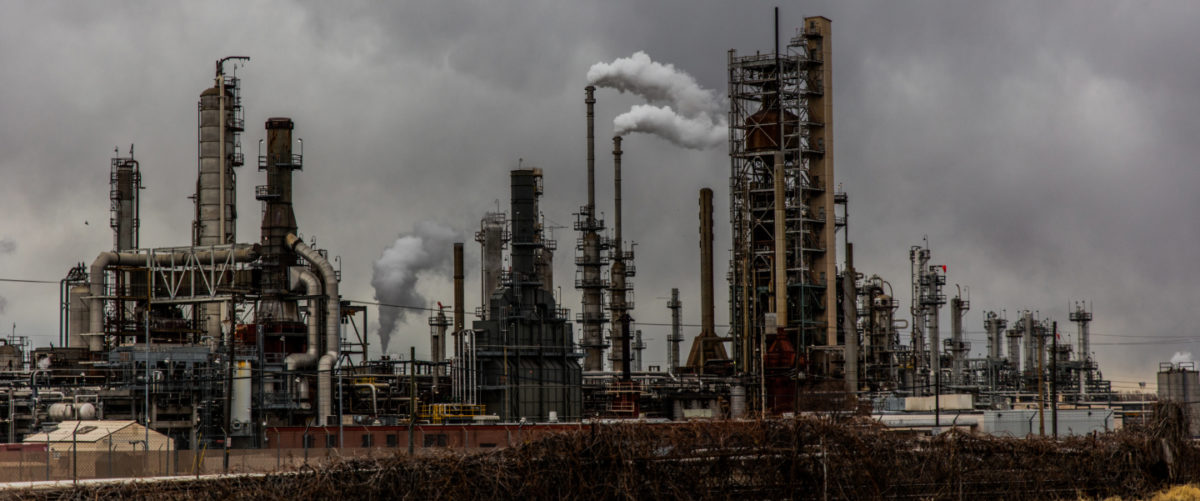 Smokestacks and their plumes of pollution rise over a gray sky.