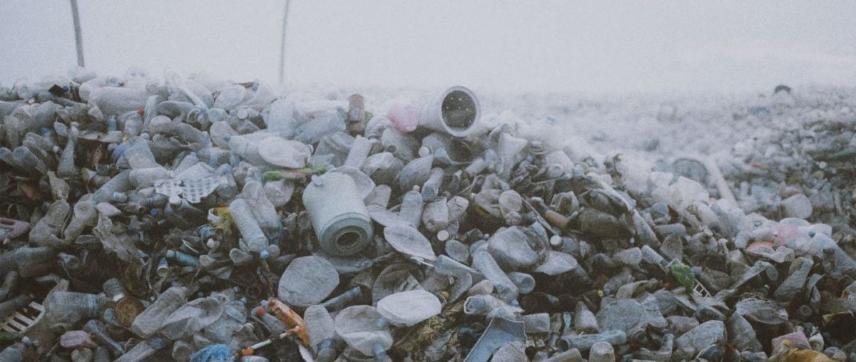 A large mountain of plastic trash sits in front of a grey sky.