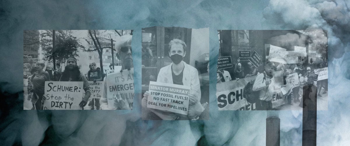 Protestors stand holding signs in front of a background of smoke and smokestacks.