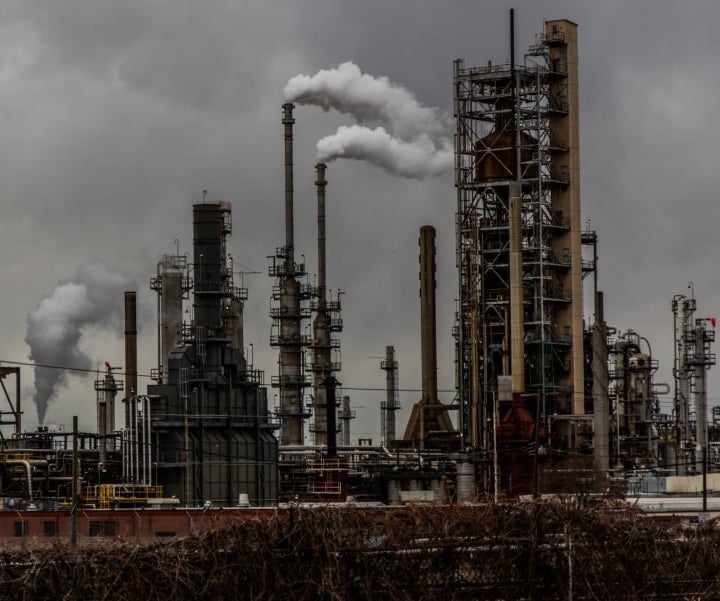 Brown, dark smokestacks rise over gray skies. The factory farm gas industry will support the dominance of dirty fuels and Big Oil.