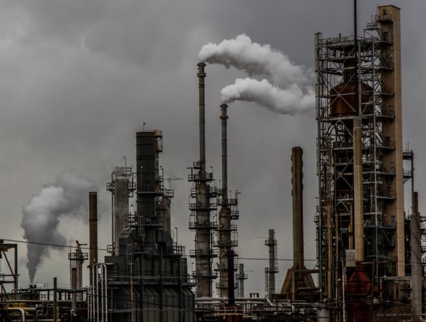 Dark smokestacks and piping rise over a gray sky.