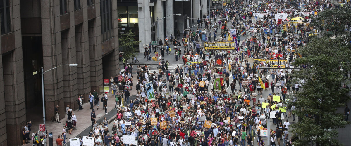 A huge crowd of people walk down a street in New York City during the 2014 People's Climate March.