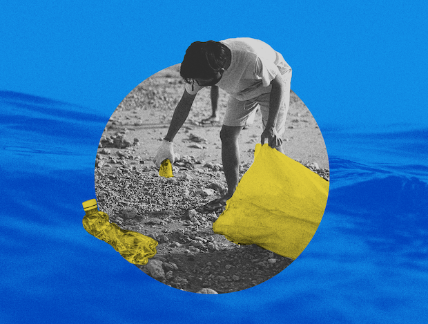 A person on a beach gathers plastic into a large bag.