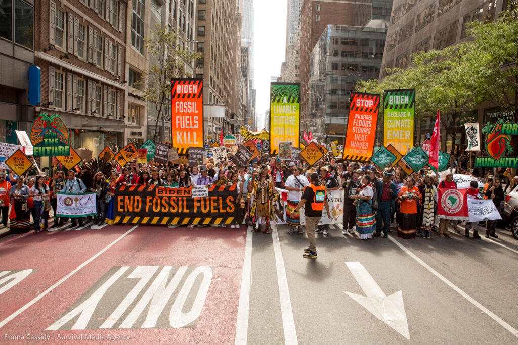 Indigenous activists at the March to End Fossil Fuels take up the whole street. They hold signs reading "BIDEN END FOSSIL FUELS," "FOR THE FUTURE," and 'FURE HUMANITY."