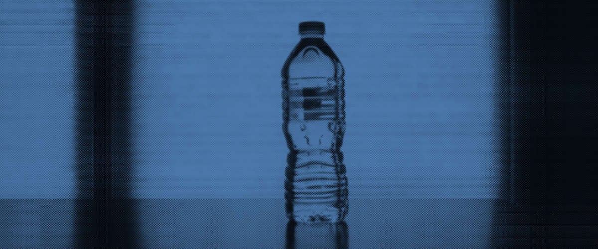 A plastic bottle of water stands in shadow.