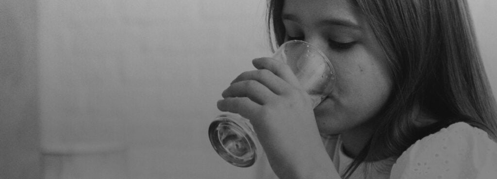 Conclusion and Recommendations for the PFAS problems [a young caucasian girl drinks from a glass of water in this black and white photo]