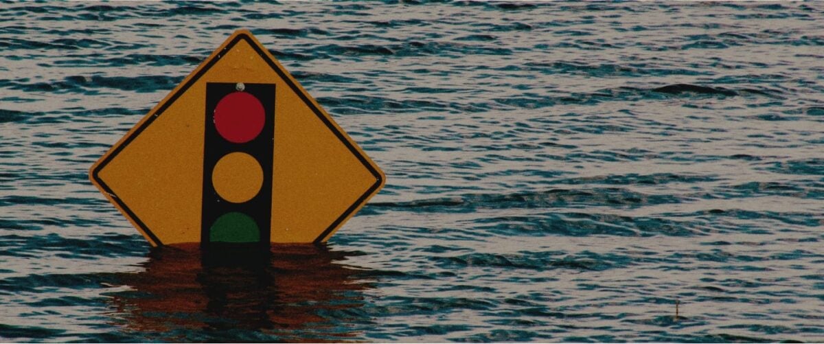 Flood waters start to cover the bottom of a yellow traffic sign.