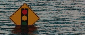 Flood waters start to cover the bottom of a yellow traffic sign.