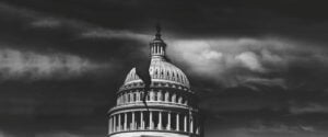 U.S. Capitol Building under ominous dark skies with a large visible crack running through the structure.